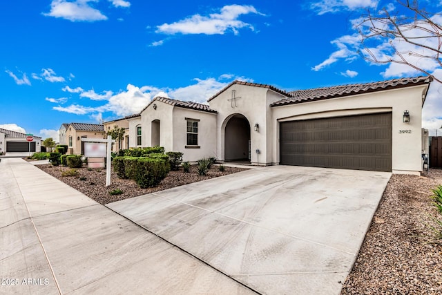 mediterranean / spanish house with stucco siding, concrete driveway, an attached garage, and a tile roof