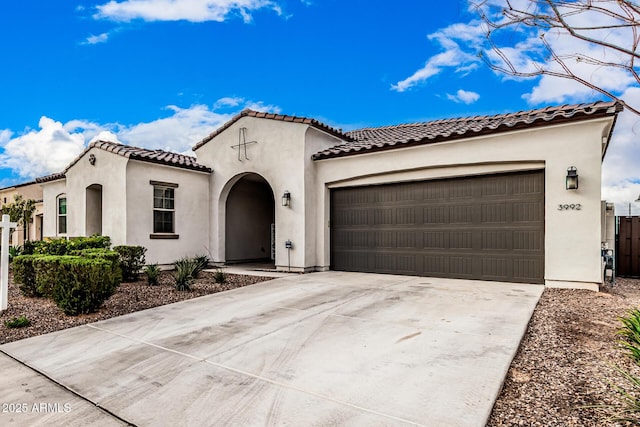 mediterranean / spanish-style home with stucco siding, concrete driveway, a tile roof, and a garage