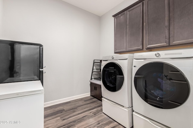 laundry room with cabinet space, washer and dryer, baseboards, and wood finished floors