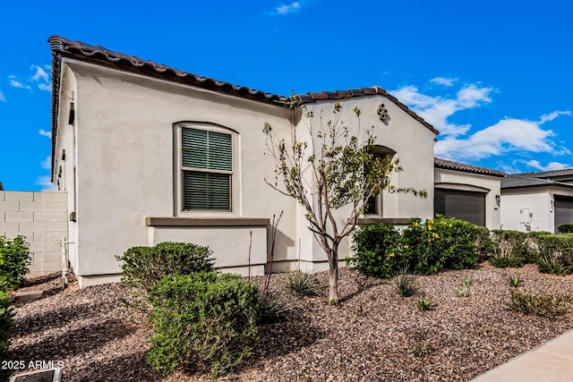 view of front of house featuring a tiled roof, a garage, and stucco siding