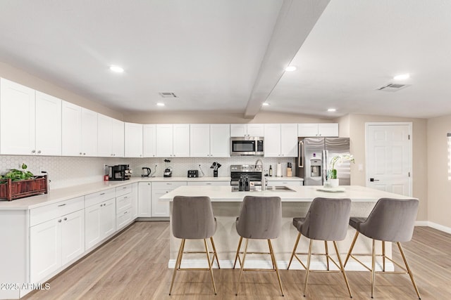kitchen with decorative backsplash, stainless steel appliances, a breakfast bar area, and light wood-type flooring