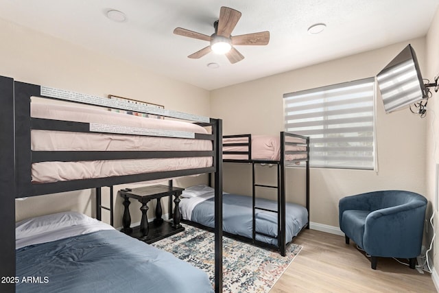 bedroom featuring baseboards, wood finished floors, and a ceiling fan