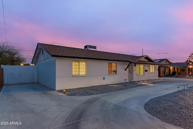 single story home featuring driveway, stucco siding, and roof with shingles