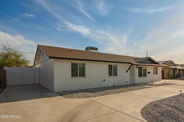 view of front of house featuring concrete driveway, stucco siding, and roof with shingles