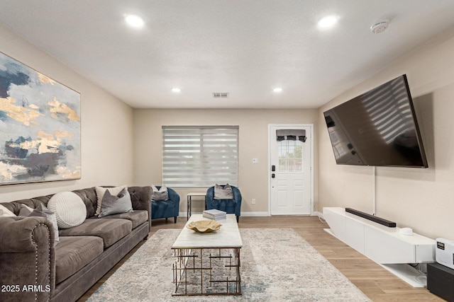living area with baseboards, visible vents, wood finished floors, and recessed lighting