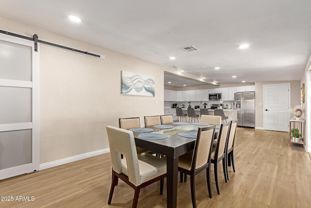 dining area with visible vents, baseboards, recessed lighting, a barn door, and light wood-style floors