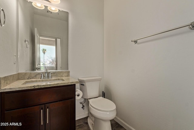 half bathroom featuring vanity, baseboards, wood finished floors, and toilet