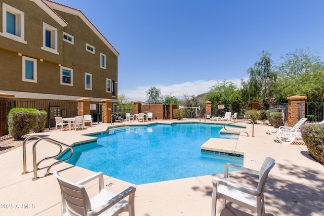 pool with a patio area and fence
