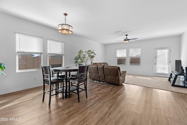 dining area with baseboards, visible vents, light wood finished floors, and ceiling fan with notable chandelier