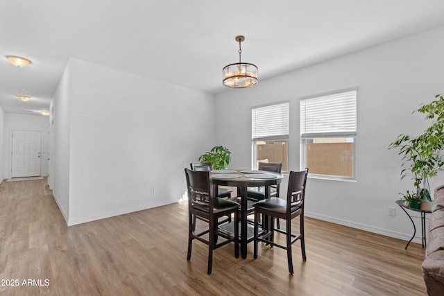 dining space featuring an inviting chandelier, light wood-style flooring, and baseboards