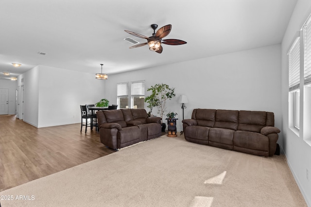 living room with visible vents, carpet, a ceiling fan, and baseboards