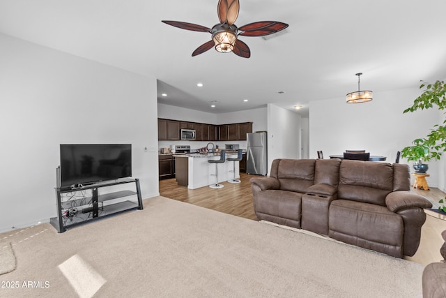 living room featuring light carpet, baseboards, a ceiling fan, and recessed lighting