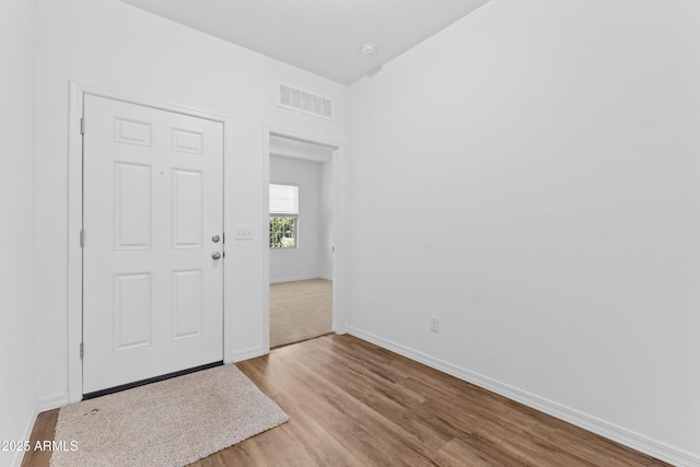 foyer entrance with baseboards, visible vents, and wood finished floors