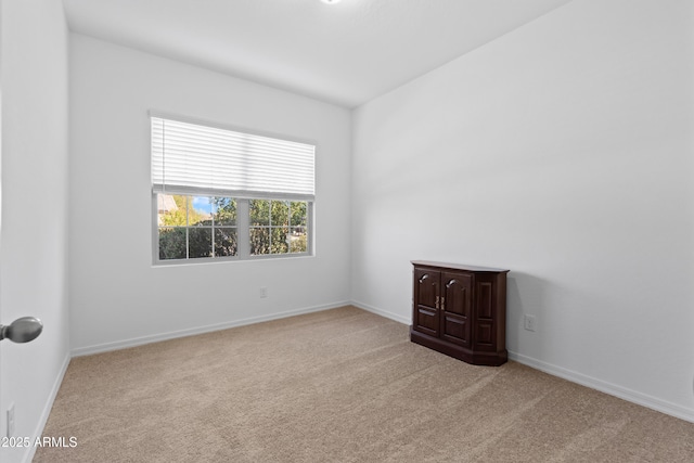 spare room featuring carpet floors and baseboards