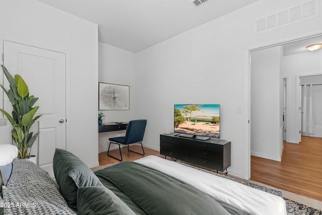 bedroom featuring wood finished floors, visible vents, and baseboards