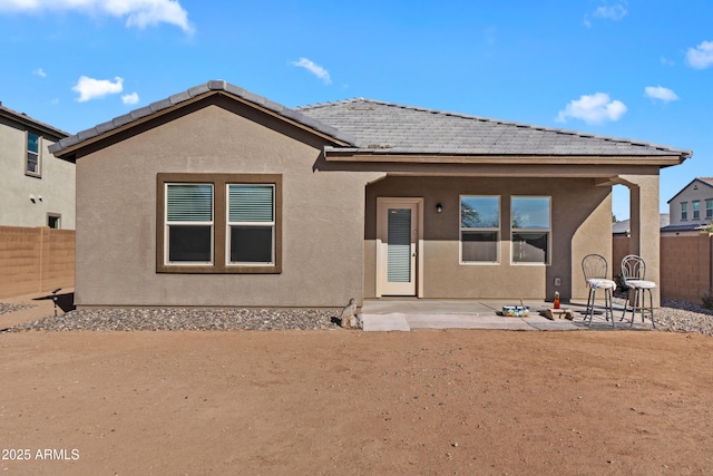 rear view of house featuring a tile roof, a fenced backyard, a patio, and stucco siding