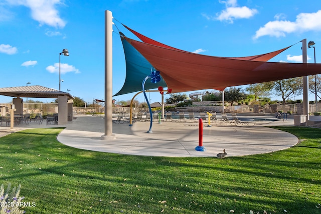 view of community featuring playground community, a lawn, and fence