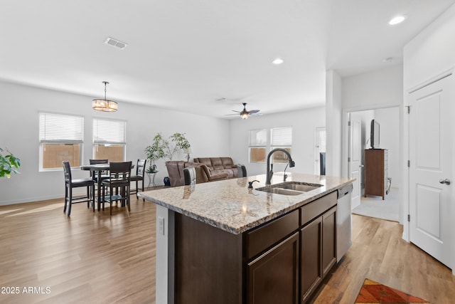 kitchen featuring visible vents, dishwasher, dark brown cabinets, light wood-type flooring, and a sink