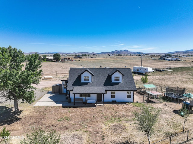 view of front facade featuring a mountain view, a rural view, a patio area, and a trampoline