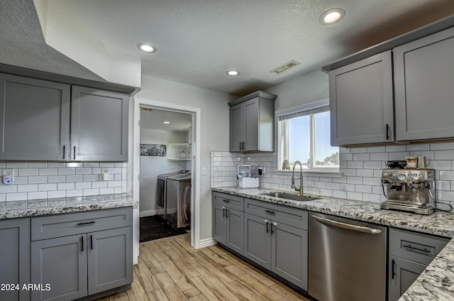 kitchen with dishwasher, sink, light hardwood / wood-style flooring, gray cabinets, and independent washer and dryer