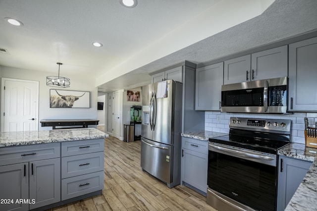 kitchen featuring light stone counters, light hardwood / wood-style flooring, and appliances with stainless steel finishes