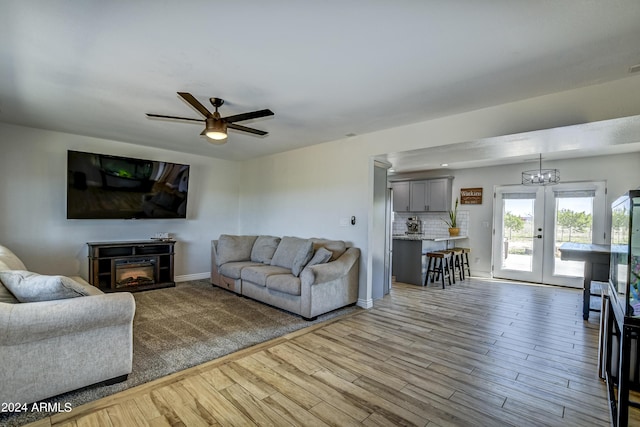 living room featuring ceiling fan with notable chandelier, wood-type flooring, and french doors