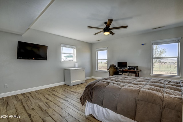 bedroom with ceiling fan, light hardwood / wood-style floors, and fridge