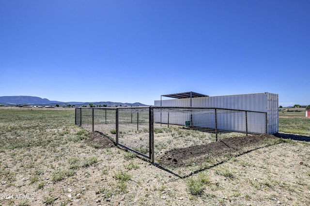 view of yard with a mountain view, a rural view, and an outbuilding