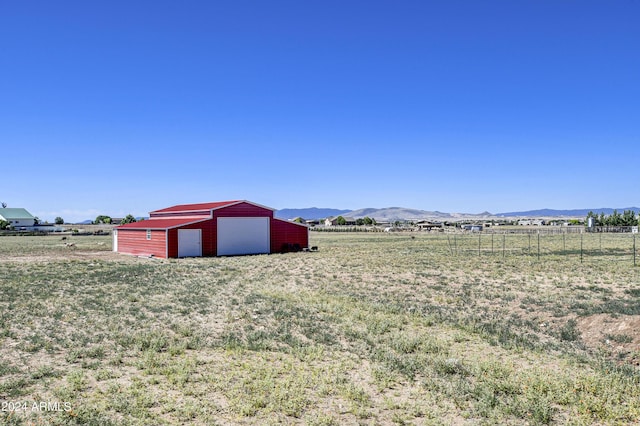 view of yard featuring a mountain view, a rural view, and an outbuilding