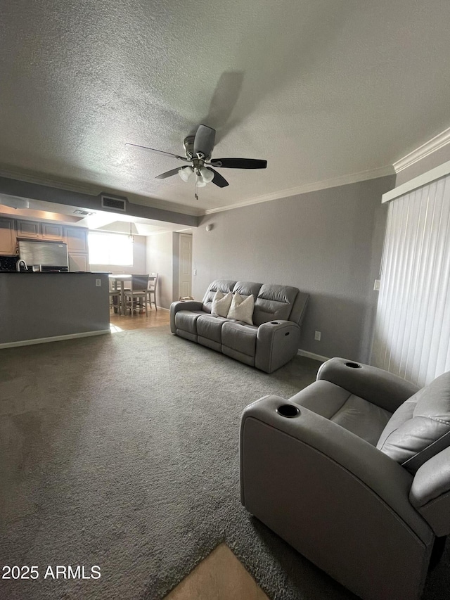 carpeted living room featuring a textured ceiling, ceiling fan, and crown molding