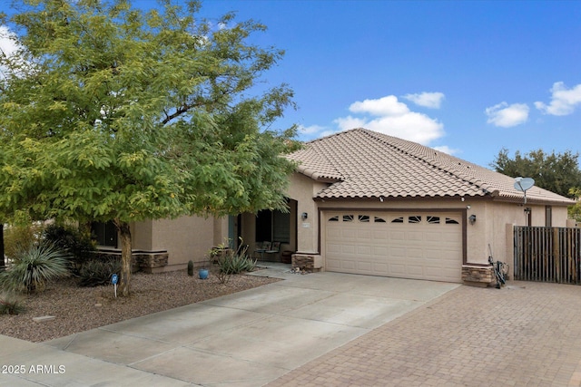 view of front of home featuring stucco siding, concrete driveway, fence, a garage, and a tiled roof