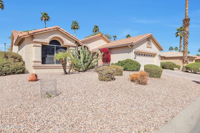 view of front of home featuring an attached garage, driveway, a tile roof, and stucco siding