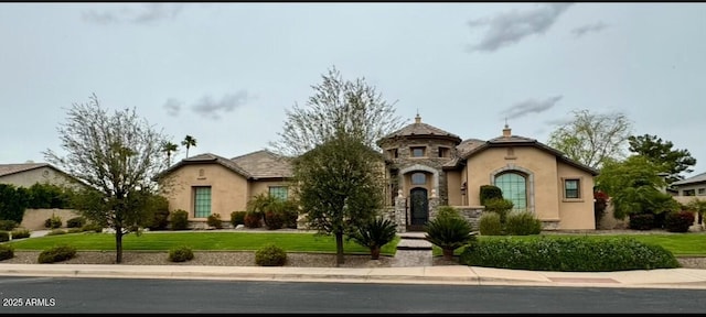 view of front facade featuring stucco siding, stone siding, a front yard, and a tiled roof