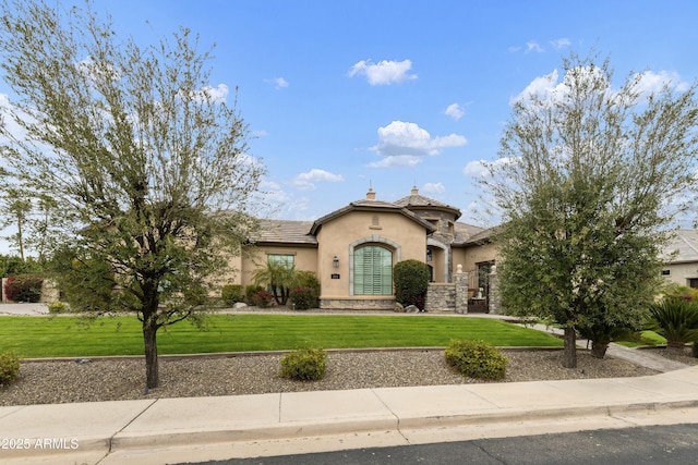 mediterranean / spanish home featuring a chimney, stucco siding, a front lawn, stone siding, and a tile roof