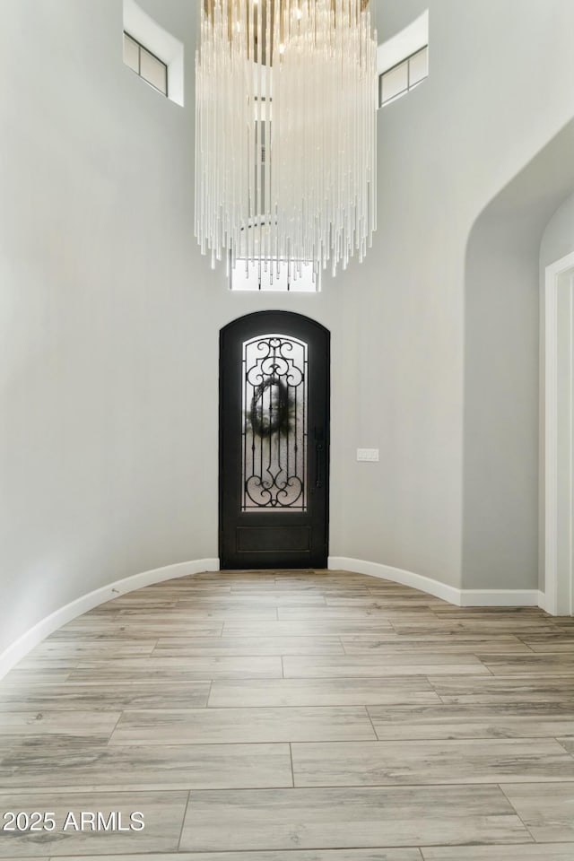 foyer with baseboards, a high ceiling, and arched walkways