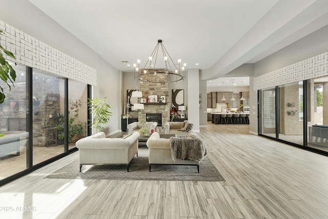 living area with a fireplace, an inviting chandelier, and light wood-style floors