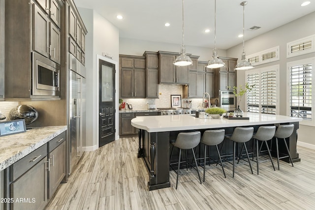 kitchen with a kitchen bar, light countertops, tasteful backsplash, and appliances with stainless steel finishes