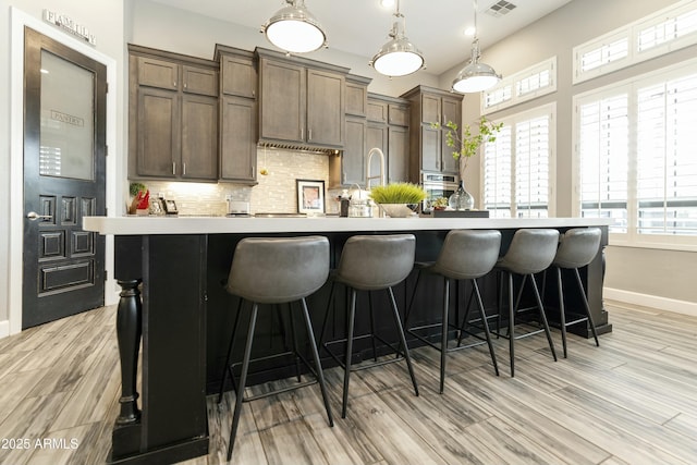 kitchen featuring baseboards, backsplash, a healthy amount of sunlight, and an island with sink