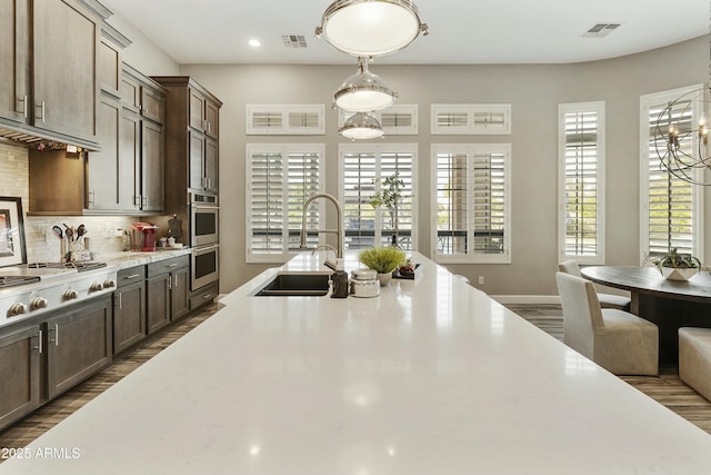 kitchen with tasteful backsplash, visible vents, stainless steel appliances, and a sink