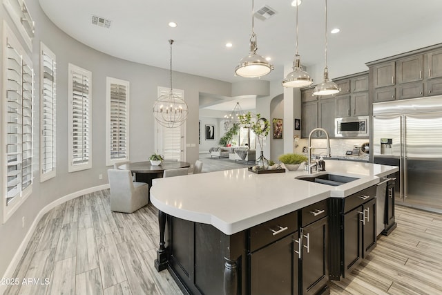 kitchen with an inviting chandelier, visible vents, built in appliances, and a sink