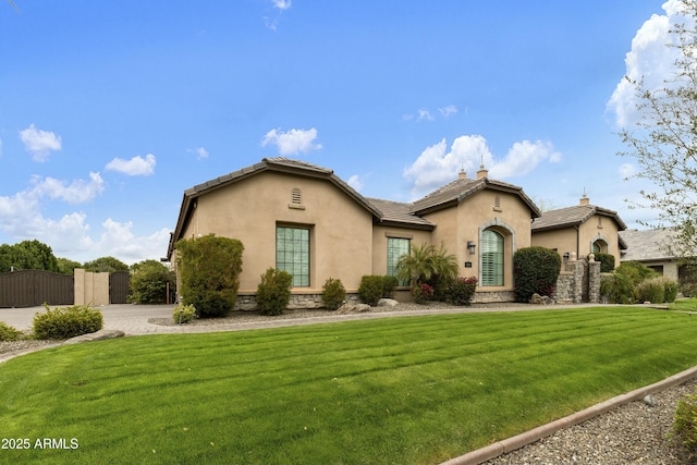 mediterranean / spanish home with stucco siding, a tile roof, a front yard, and a gate