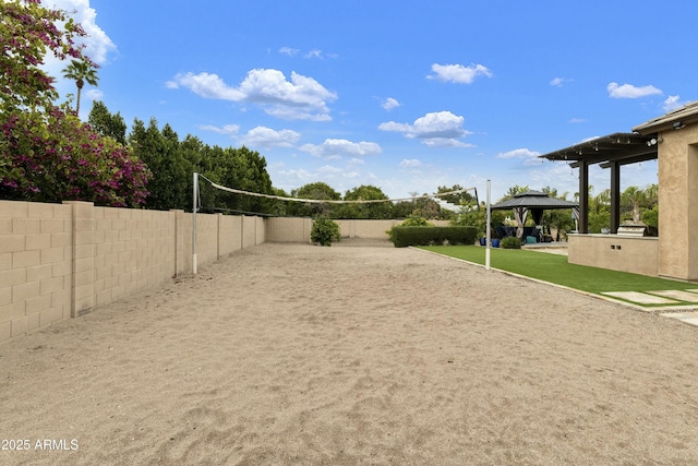 view of yard with a gazebo, fence, and volleyball court