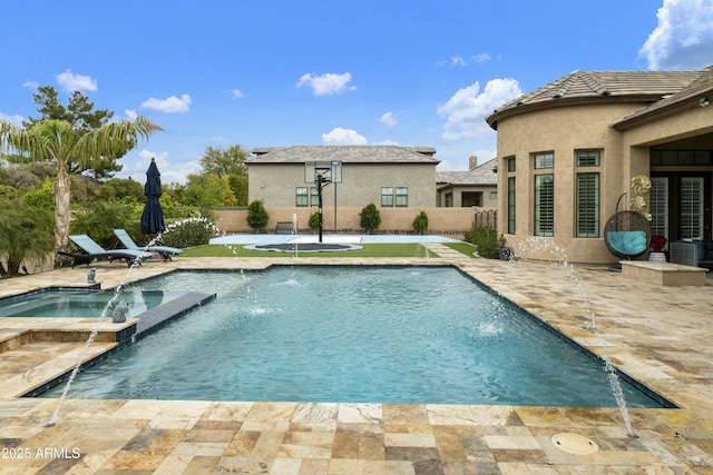 view of pool with a patio area, fence, and a pool with connected hot tub