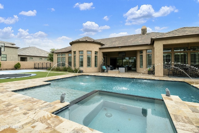 view of pool with a patio area, a pool with connected hot tub, and fence