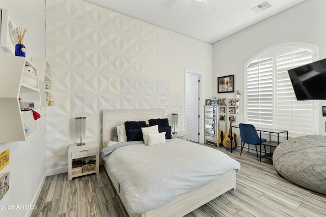 bedroom featuring visible vents, baseboards, and wood finished floors