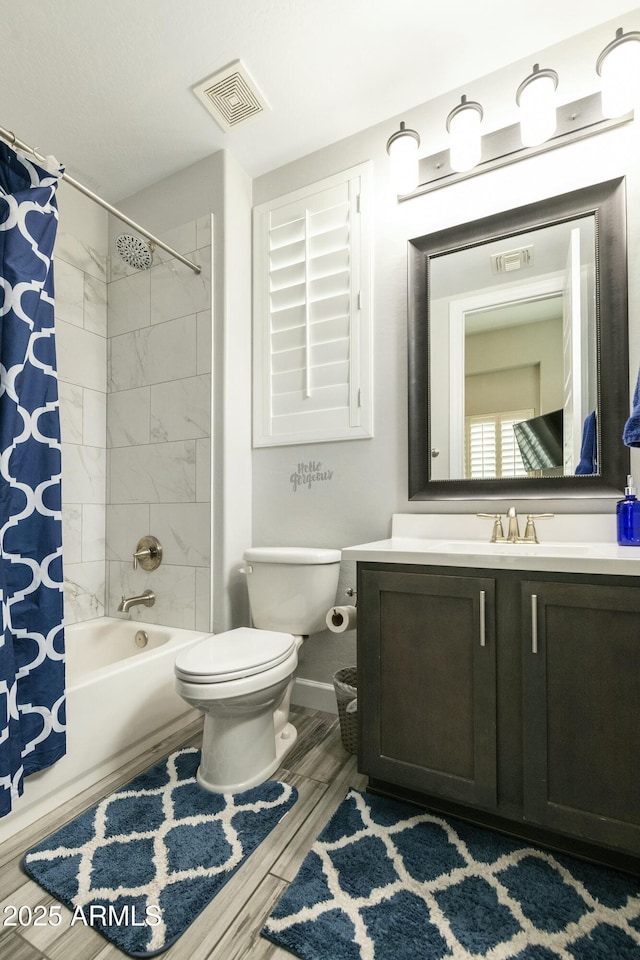 full bathroom featuring visible vents, wood tiled floor, shower / bath combo with shower curtain, toilet, and vanity