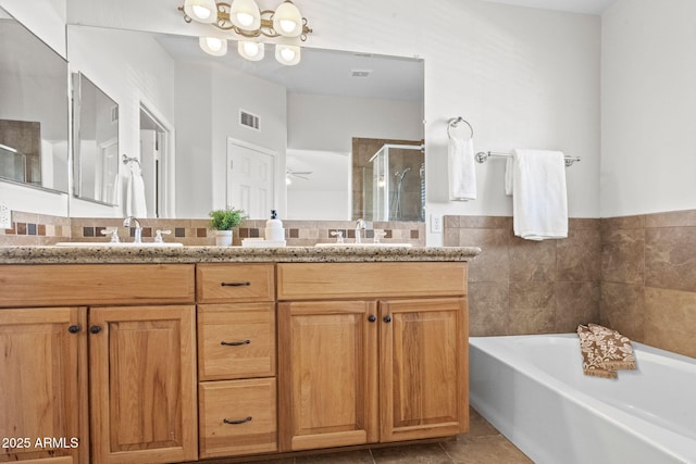 bathroom featuring tile walls, tile patterned floors, ceiling fan, separate shower and tub, and vanity