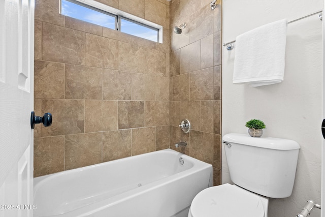 bathroom featuring tiled shower / bath combo and toilet