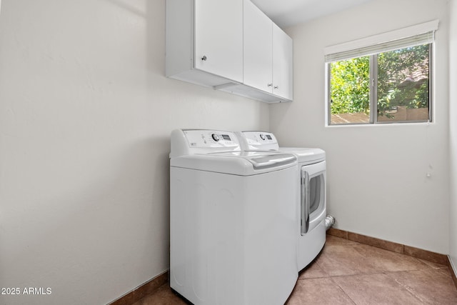 clothes washing area with washing machine and dryer, light tile patterned floors, and cabinets