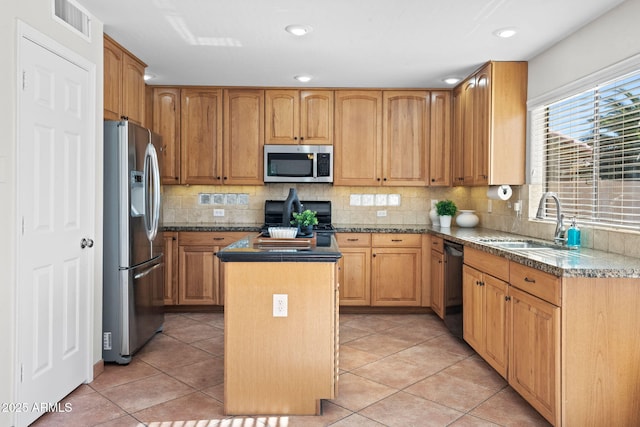 kitchen with appliances with stainless steel finishes, light tile patterned flooring, a kitchen island, sink, and backsplash